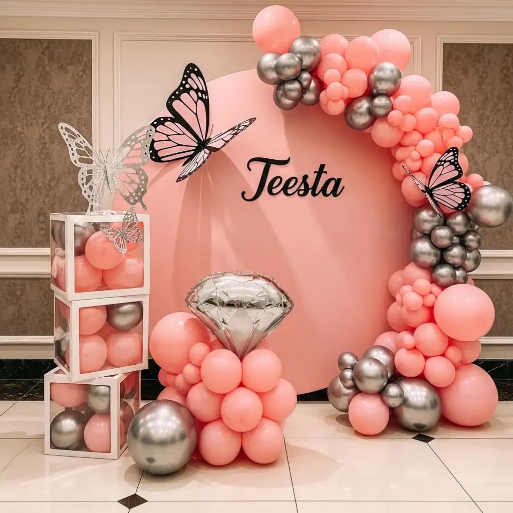 Whimsical pink-themed celebration setup featuring a circular backdrop with “Teesta” in cursive, pink and silver balloon garlands, large butterfly accents, and transparent balloon boxes—perfect for a dreamy, personalized party.